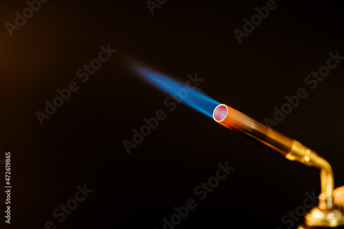 Blue flame from a gas brass torch burner on black background photo