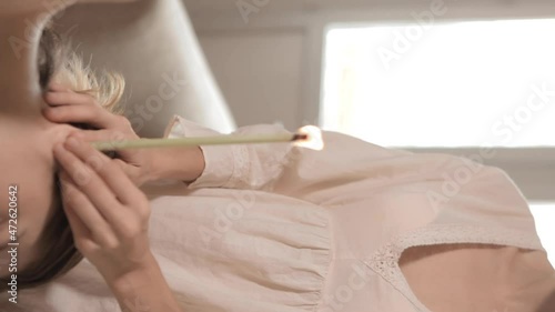 Beautiful woman receiving ear candle treatment. Therapist performing an ear wax treatment on a patient using candling. Naked woman receiving ear candle treatment from masseur 