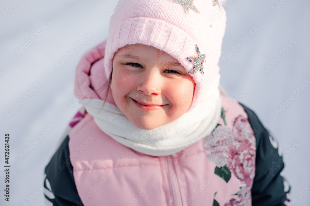 Happy little girl. Portrait of child in winter warm pink clothes basking in sun on walk on frosty morning in nature. Happy little girl. Portrait of child in winter warm pink clothes basking in sun on walk on frosty morning in nature.