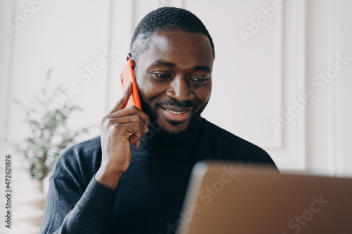 Tablou canvas Cheerful young man with African lineage commerce businessowner calling to suppli
