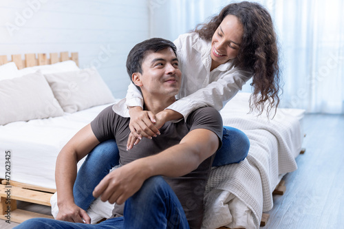 Happy young couple hugging and laughing in bedroom.