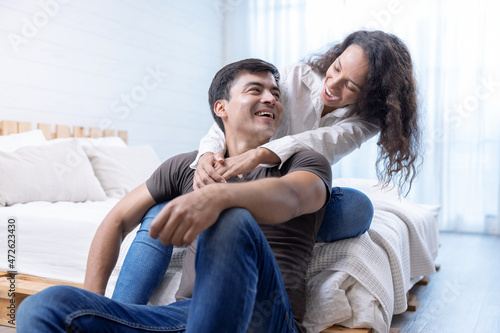 Happy young couple hugging and laughing in bedroom.