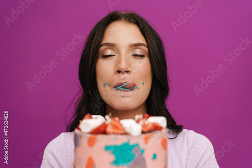Young brunette woman wearing t-shirt eating birthday cake