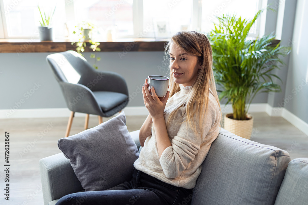 Shot of a young woman having coffee at home. Portrait of a young woman enjoying a warm beverage at home. Wake up and smell the coffee. Young coffee lover sniffing hot drink at cozy home interior Shot of a young woman having coffee at home. Portrait of a young woman enjoying a warm beverage at home. Wake up and smell the coffee. Young coffee lover sniffing hot drink at cozy home interior