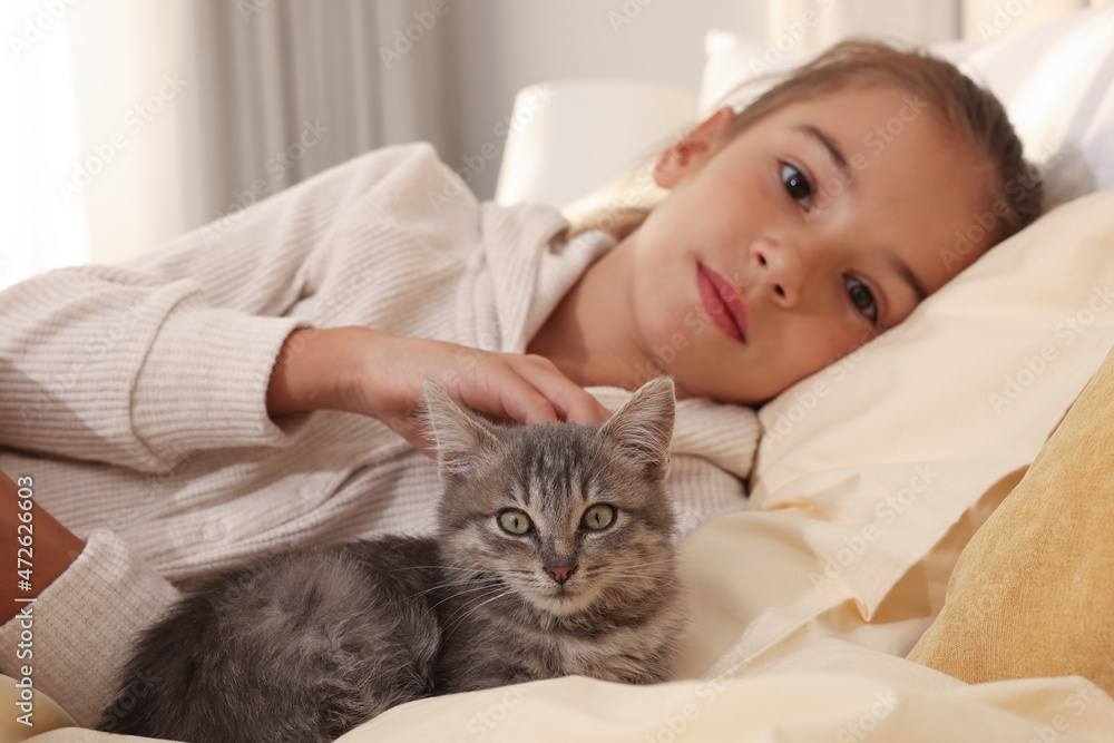Cute little child with kitten at home, focus on pet Cute little child with kitten at home, focus on pet
