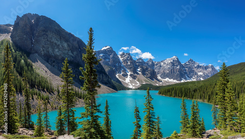 Panoramic view of the Moraine Lake with snow-covered peaks above it in Rocky Mountains, Banff National Park, Canada.