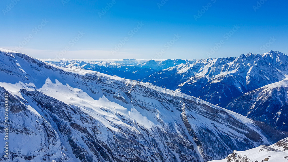 A beautiful and serene landscape of mountains covered with snow. Thick snow covers the slopes. Clear weather. Sharp slopes of the mountains covered with snow, with partially visible rocks. A beautiful and serene landscape of mountains covered with snow. Thick snow covers the slopes. Clear weather. Sharp slopes of the mountains covered with snow, with partially visible rocks.
