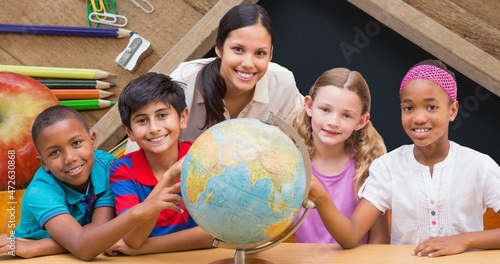 Portrait of smiling teacher and students learning about planet earth on globe