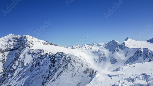 A beautiful and serene landscape of mountains covered with snow. Thick snow covers the slopes. Clear weather. Sharp slopes of the mountains covered with snow  with partially visible rocks.