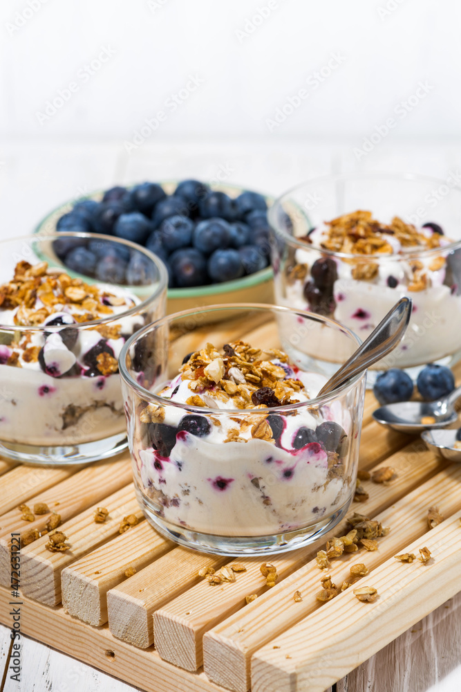 glasses with healthy breakfast with blueberries, yogurt and granola, vertical