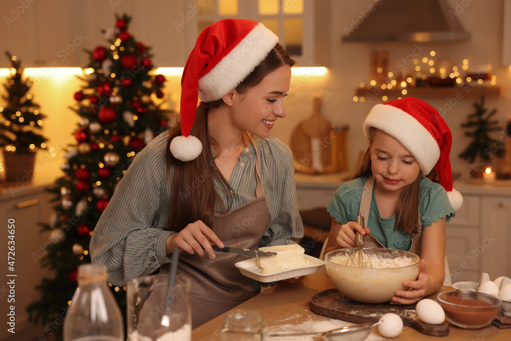 Mother with her cute little daughter making dough for Christmas cookies in kitchen Mother with her cute little daughter making dough for Christmas cookies in kitchen