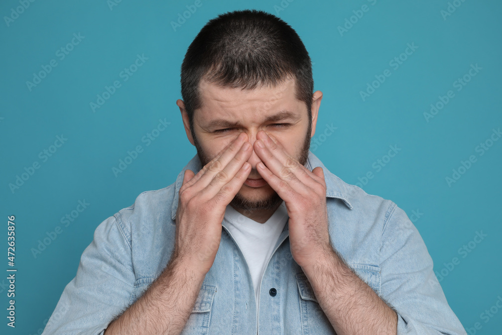 Man suffering from headache on light blue background Man suffering from headache on light blue background