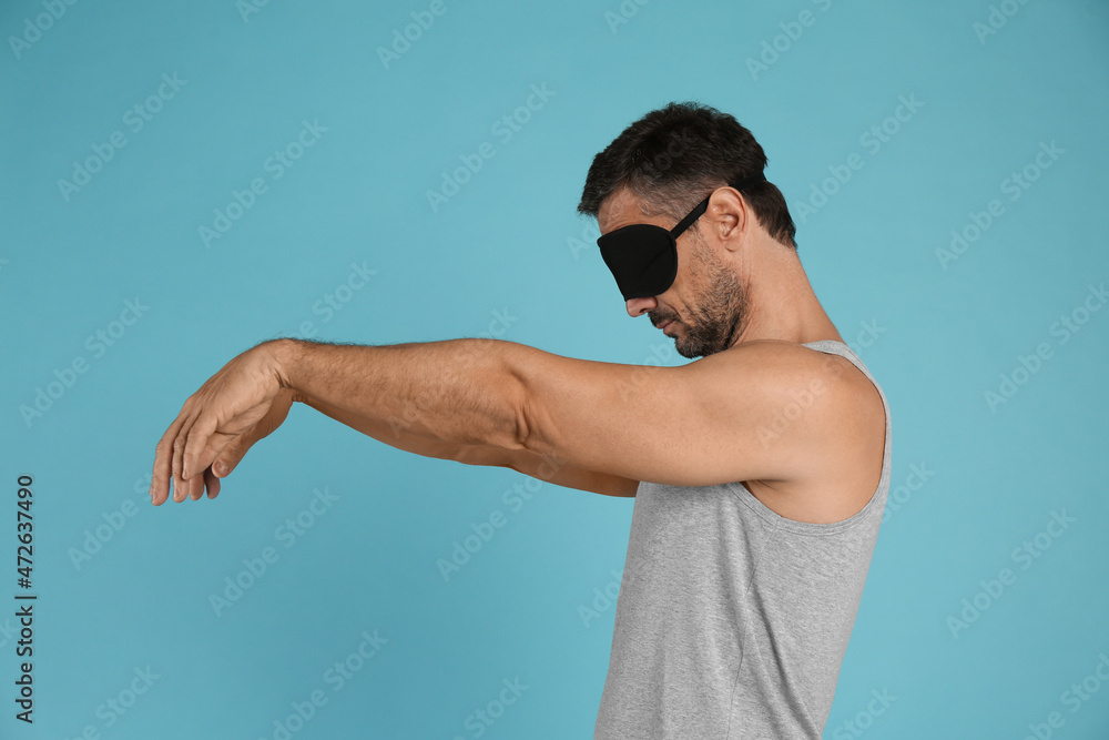Man with eye mask in sleepwalking state on light blue background Man with eye mask in sleepwalking state on light blue background