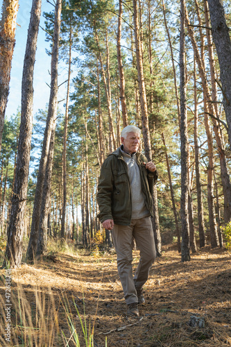 Peaceful elderly man enjoying the nature while spending time at the woods at the autumn