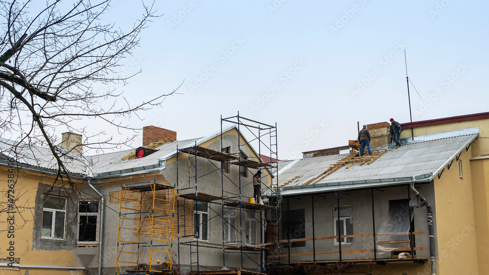 Construction workers put shingles on a roof. Workman install new roof on old building. Construction workers put shingles on a roof. Workman install new roof on old building.