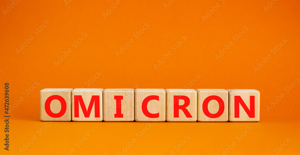 Fototapeta premium Covid-19 new omicron strain symbol. The concept word Omicron on wooden cubes. Beautiful orange background. Copy space. Medical and COVID-19 new omicron strain variant virus concept.
