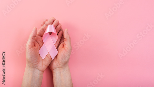 Breast cancer awareness pink background of female hands holding ribbon