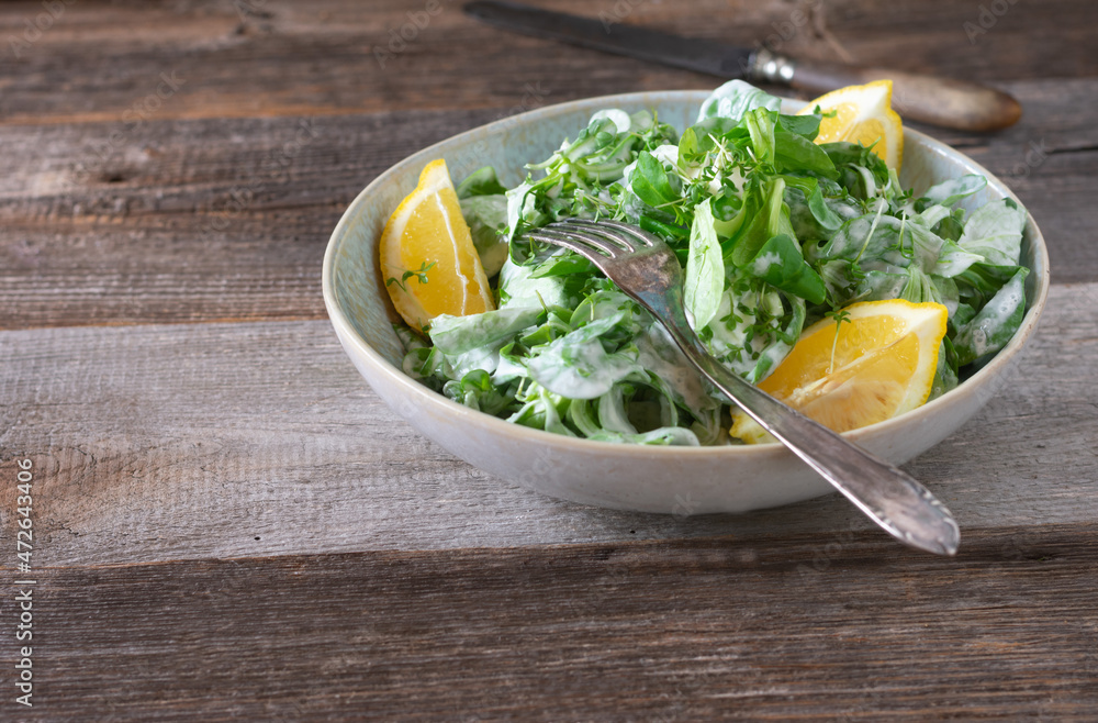 Bowl with green salad isolated on wooden table Bowl with green salad isolated on wooden table