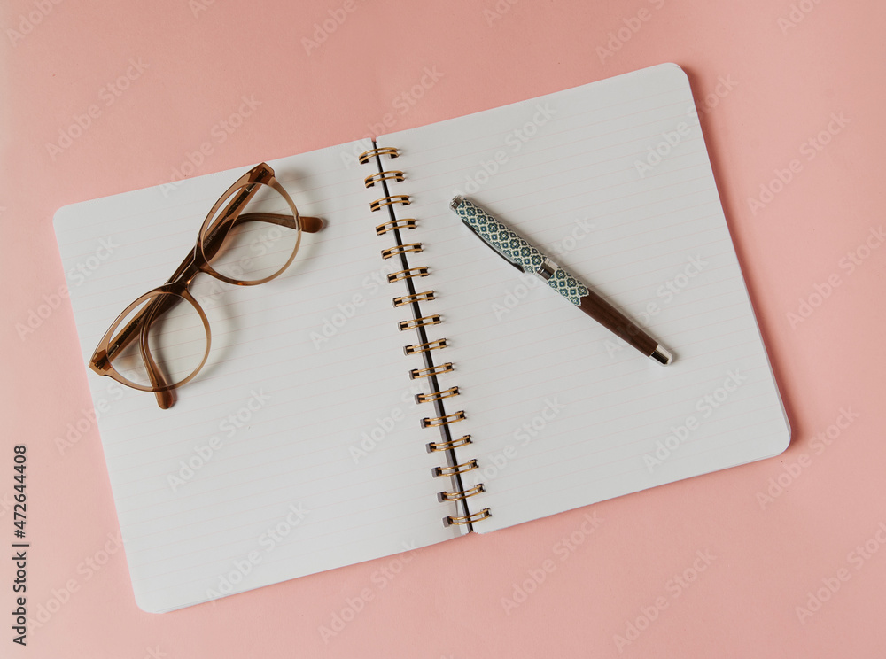 Cahier à spirales ouvert sur une page blanche pour notes, écriture et  bonnes résolution - style féminin avec lunettes et stylo plume sur fond  rose Photos | Adobe Stock