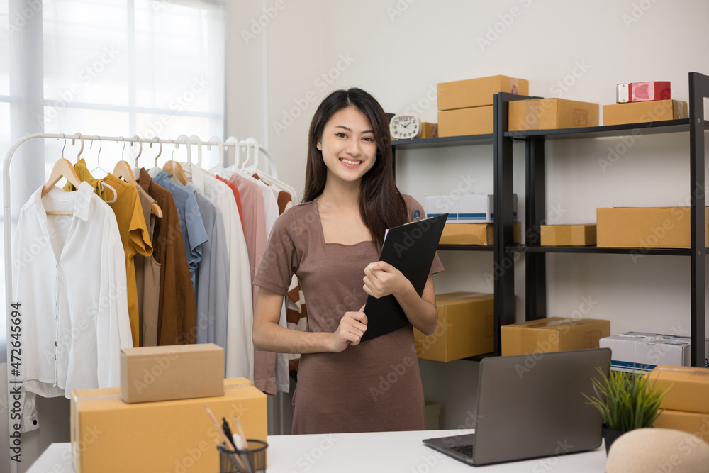 Young beautiful asian woman business owner at fashion store holding clipboard check stock on rails clothing standing and smile to camera. Asian female entrepreneur working in clothes shop. Young beautiful asian woman business owner at fashion store holding clipboard check stock on rails clothing standing and smile to camera. Asian female entrepreneur working in clothes shop.