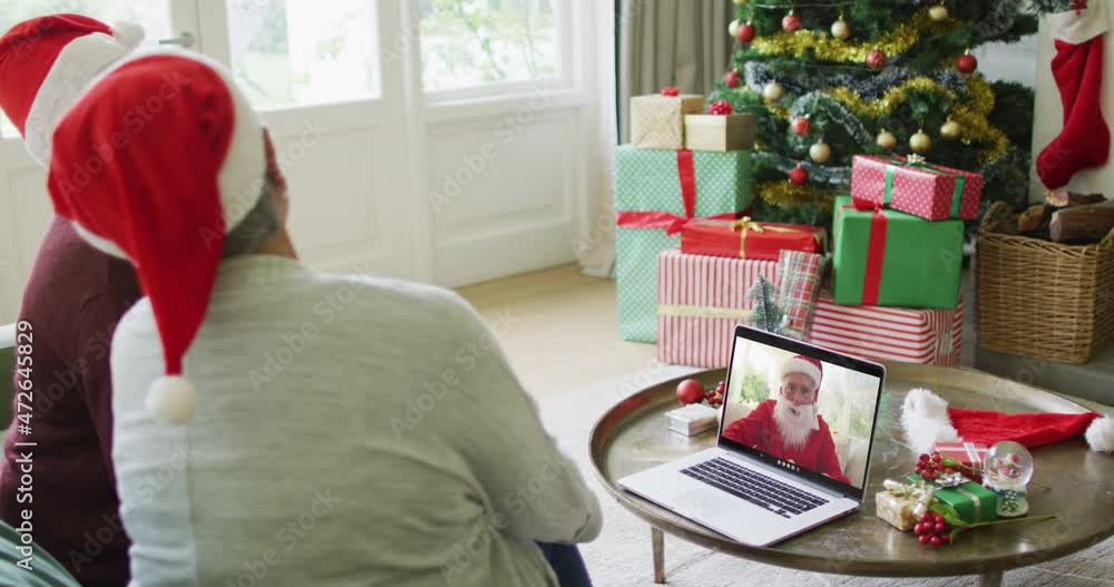 Diverse senior female friends using laptop for christmas video call with happy santa on screen Diverse senior female friends using laptop for christmas video call with happy santa on screen