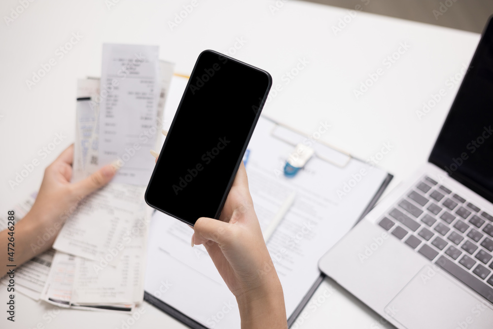 Close up woman is using a smartphone to scan the bill to calculate her income and expenses. In hand there were bills to pay a lot in debt. Purchase with scan qr code payment online. Close up woman is using a smartphone to scan the bill to calculate her income and expenses. In hand there were bills to pay a lot in debt. Purchase with scan qr code payment online.