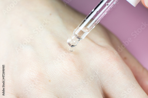 Bottle of cosmetic oil with a pipette. Close up liquid drop dripping on woman skin. Beauty, medicine and  health care concept. Macro photo. Natural, eco cosmetics.