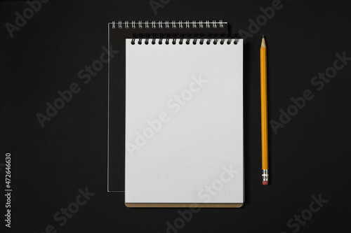 Notebook with spiral binder and pencil on a dark background, top view, copy space. Business or education minimal concept