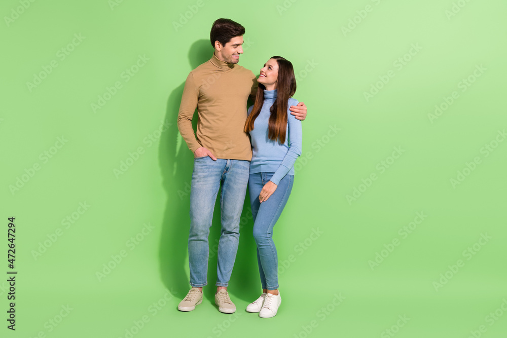 Full length portrait of peaceful idyllic people hugging have good mood isolated on green color background Full length portrait of peaceful idyllic people hugging have good mood isolated on green color background