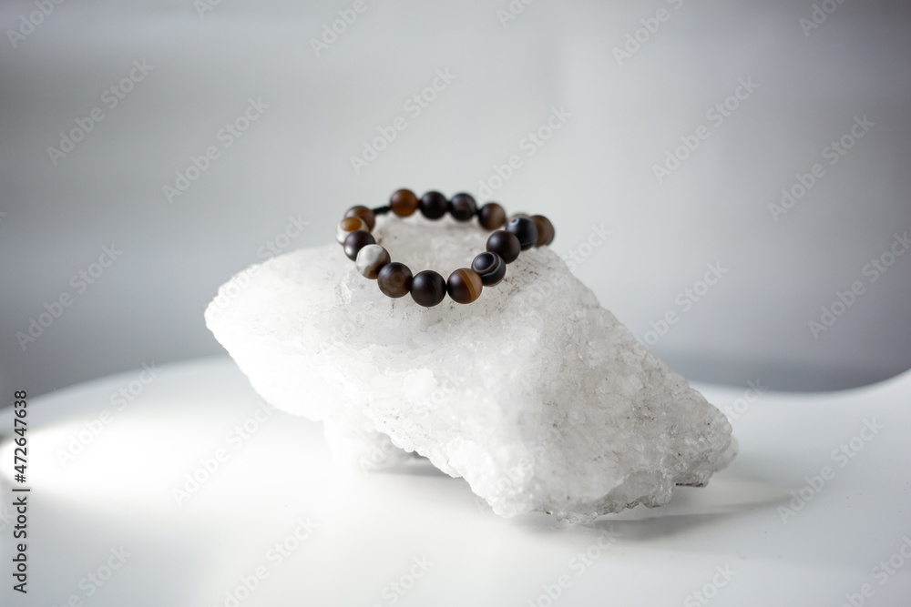 Beads from multi-colored natural stones lie on a snow-white stone, topaz and quartz