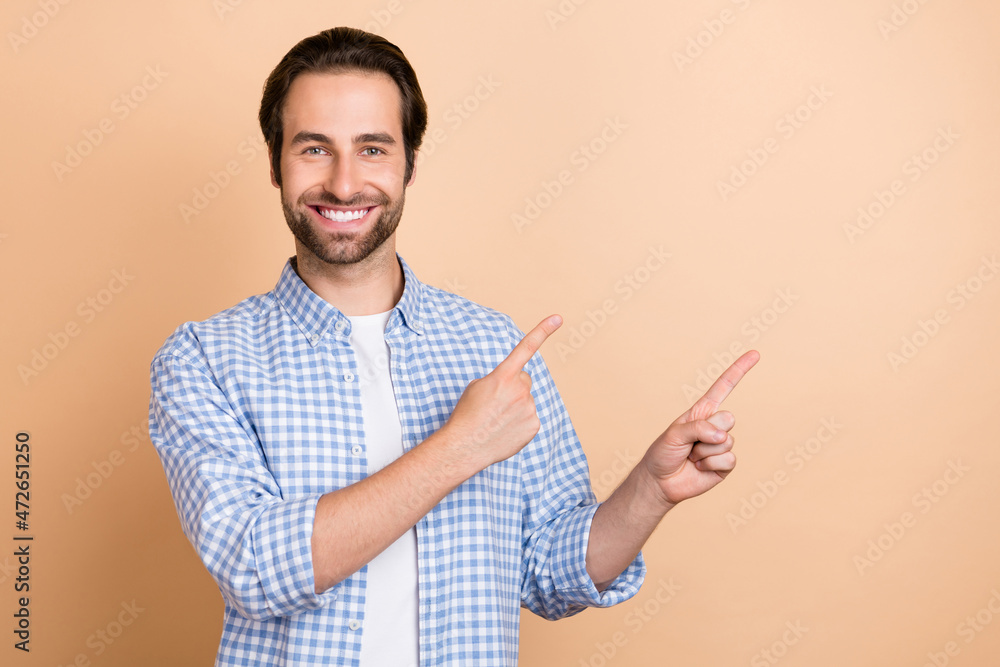 Photo of cool millennial guy index empty space wear plaid shirt isolated on beige color background Photo of cool millennial guy index empty space wear plaid shirt isolated on beige color background