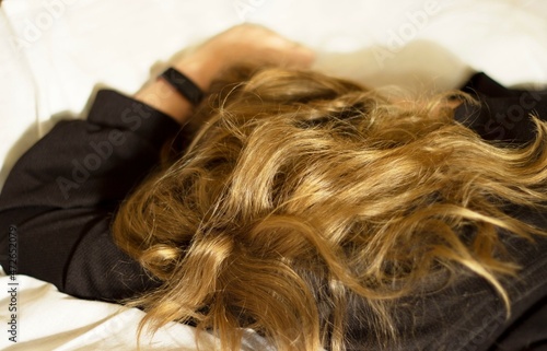 A teenage girl is resting on a bed with her hair down