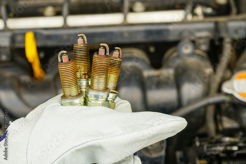 Ręka mechanika samochodowego trzymająca stare świece zapłonowe wymienione w samochodzie.