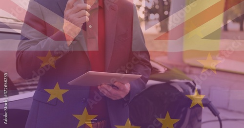 European union and british flags over businessman using tablet pc against electric car
