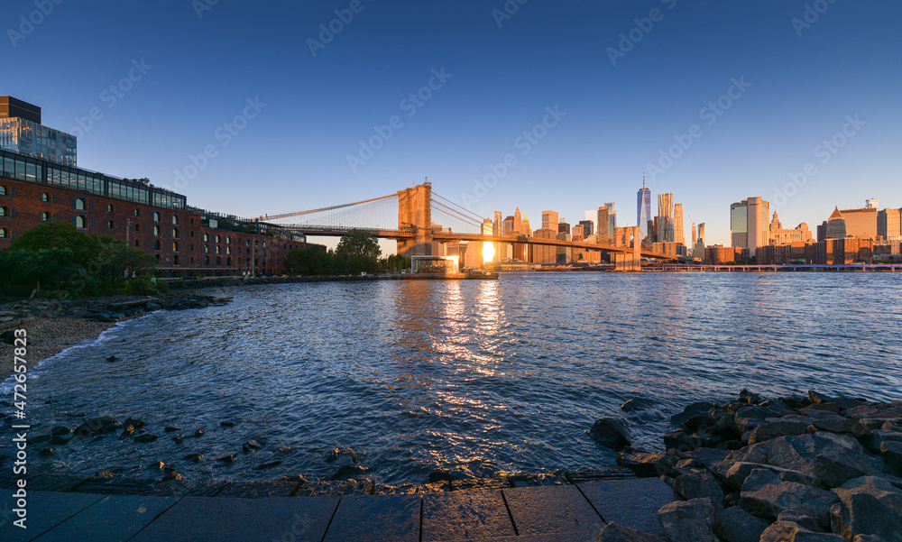 Travel to New York. The skyline of Manhattan photographed during a summer sunrise, view to Brooklyn Bridge. Landmarks of United States of America. Skyscraper office buildings.