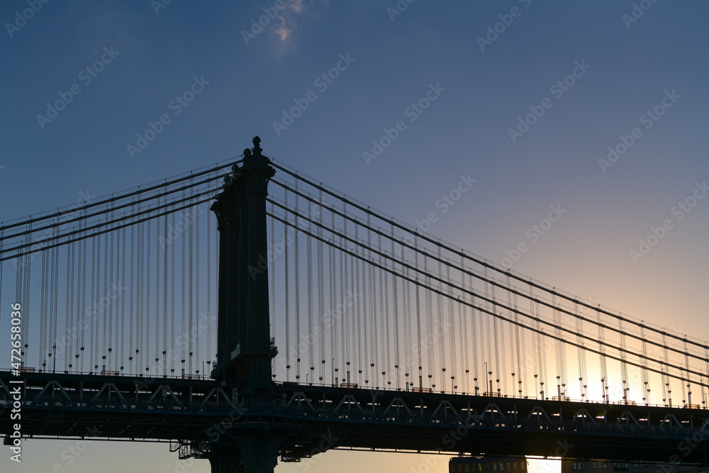 Fototapeta premium Travel to New York. The skyline of Manhattan photographed during a summer sunrise, view to Manhattan Bridge. Landmarks of United States of America. Skyscraper office buildings.