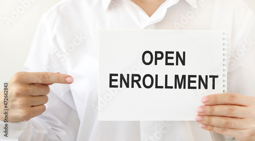 The girl points to a notebook with the text OPEN ENROLLMENT.