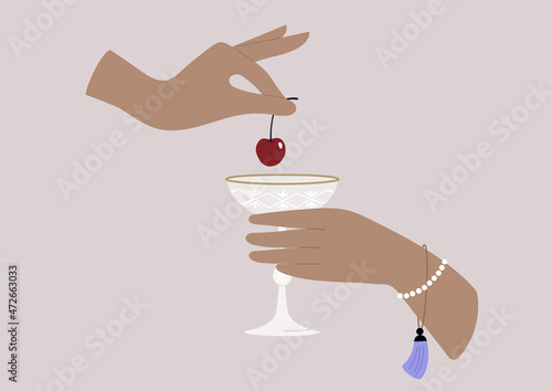 Hands putting a cherry in a champagne glass, upper class lifestyle