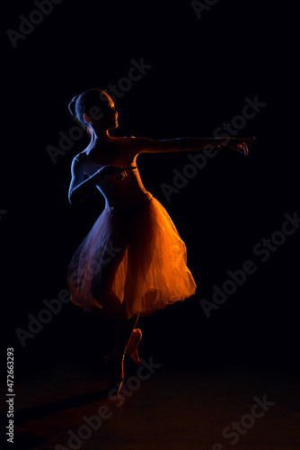 Silhouette of little ballet dancer, double exposure. Young ballerina posing in studio in mixed light. Child and dance art concept.