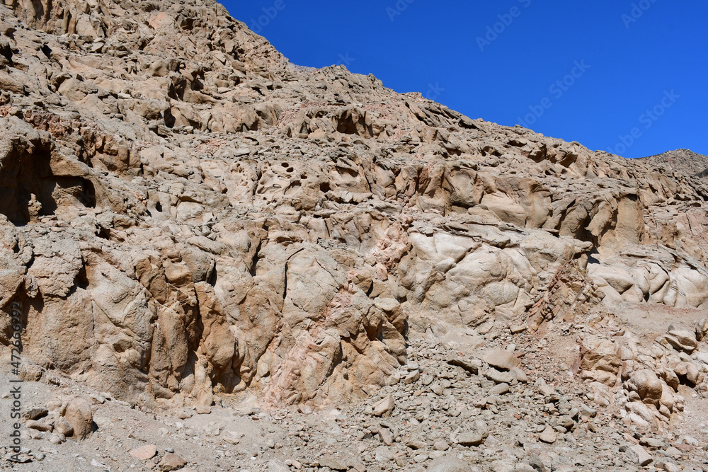 Multicolored rock with a beautiful unusual texture obtained as a result of natural weathering against a blue sky background