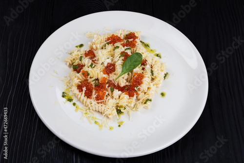 Pasta with red caviar on black wooden background