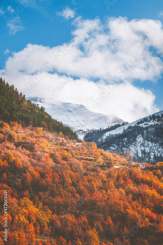 Colorful sunrise on the snowy Agrafa mountains with the colors of the fall on the trees