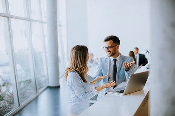 Young business couple working and discussing by laptop in the office