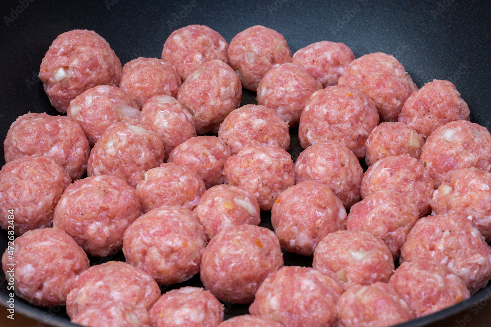 Side view on raw semi-finished minced meatballs with onion on the frying pan. Homemade food Side view on raw semi-finished minced meatballs with onion on the frying pan. Homemade food