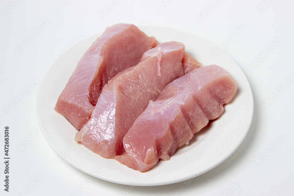 Raw turkey steaks on a white plate. Turkey breast fillet on a plate. Diet meat Raw turkey steaks on a white plate. Turkey breast fillet on a plate. Diet meat