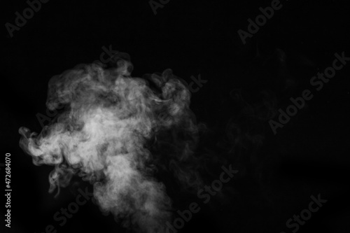 Fragment of white hot curly steam smoke isolated on a black background, close-up. Create mystical photos. Abstract background, design element
