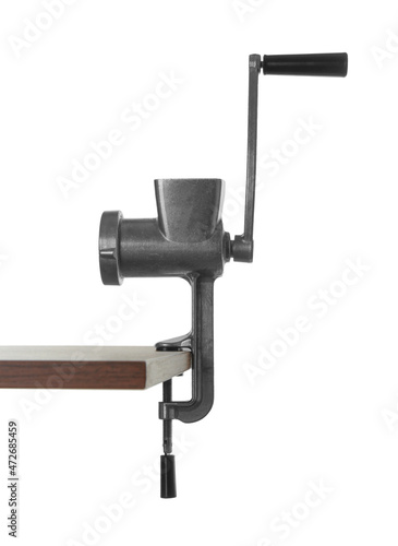 Metal manual meat grinder on table against white background