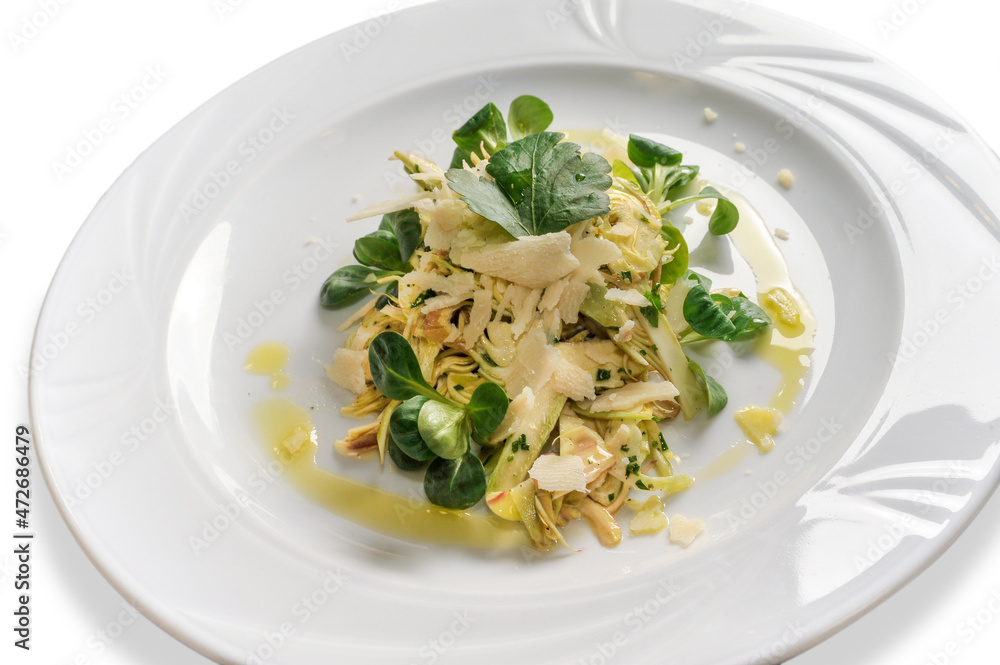 Artichoke salad with lamb's lettuce, parmesan flakes and extra virgin olive oil in white plate isolated on white