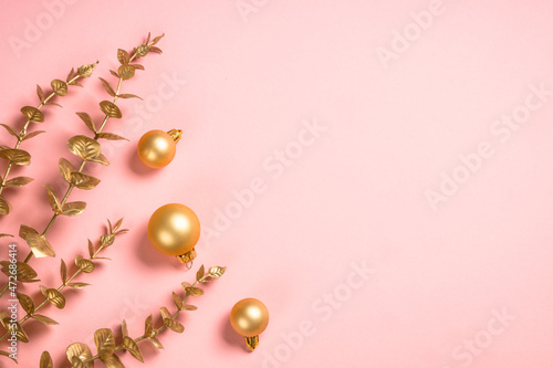Christmas composition with eucalyptus, eucalyptus branches and golden christmas decorations at pink background. Flat lay image with copy space.