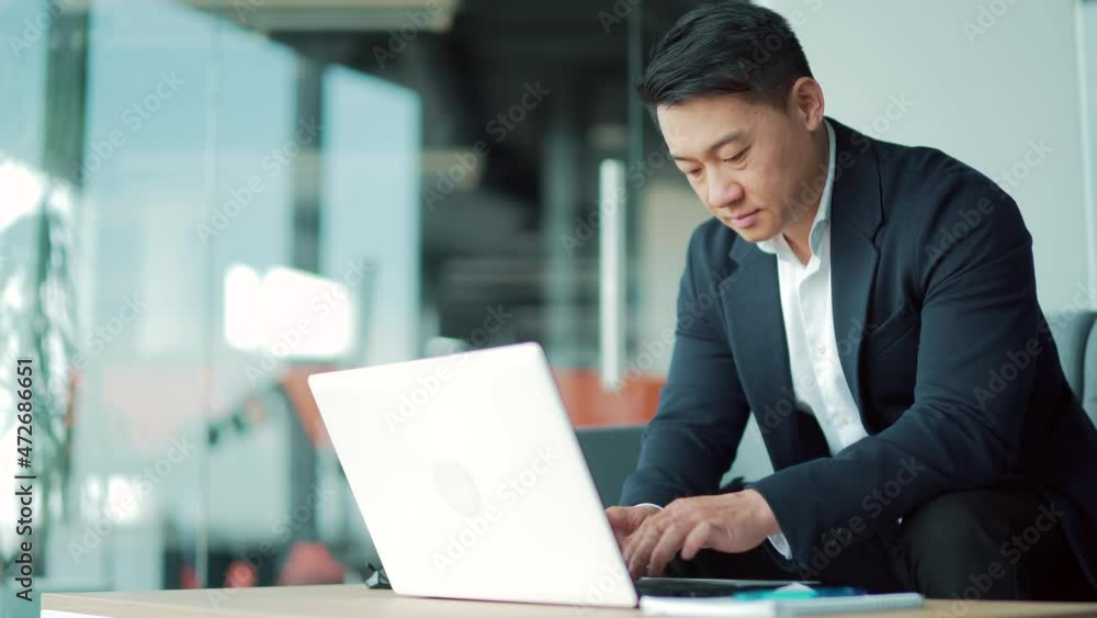 Business asian man in suit working on laptop computer in modern office coworking center. Confident Serious Male Manager Employee satisfied cheerful Busy Texting, Typing Message Employment, occupation